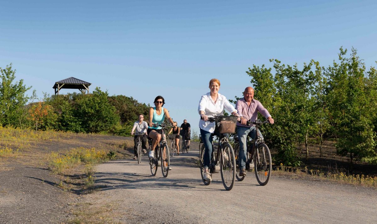 Amis heureux qui se baladent à vélo électrique sur le terril de Pecquencourt-Rieulay