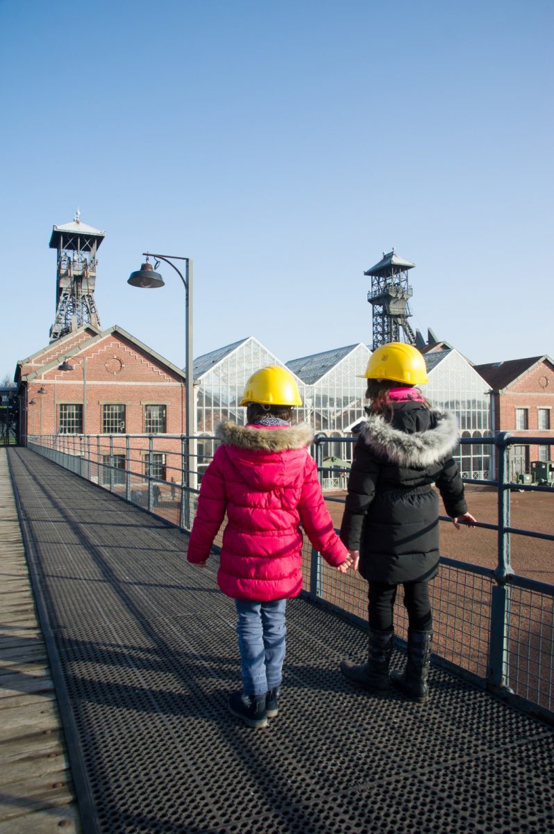 Deux enfants avec un casque de mineur sur la passerelle du Centre historique minier de Lewarde pendant une visite