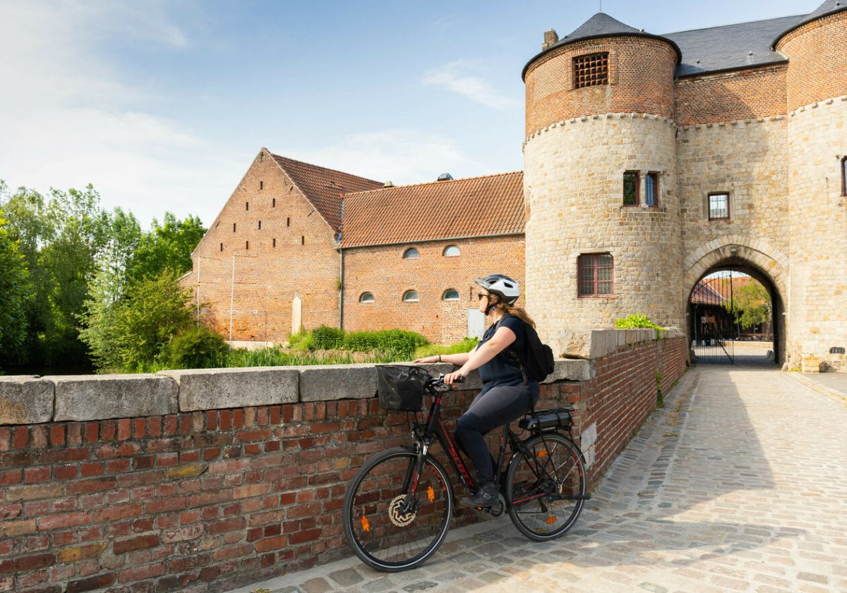 Femme qui roule à vélo sur les pavés du château de Montmorency à Montigny-en-Ostrevent