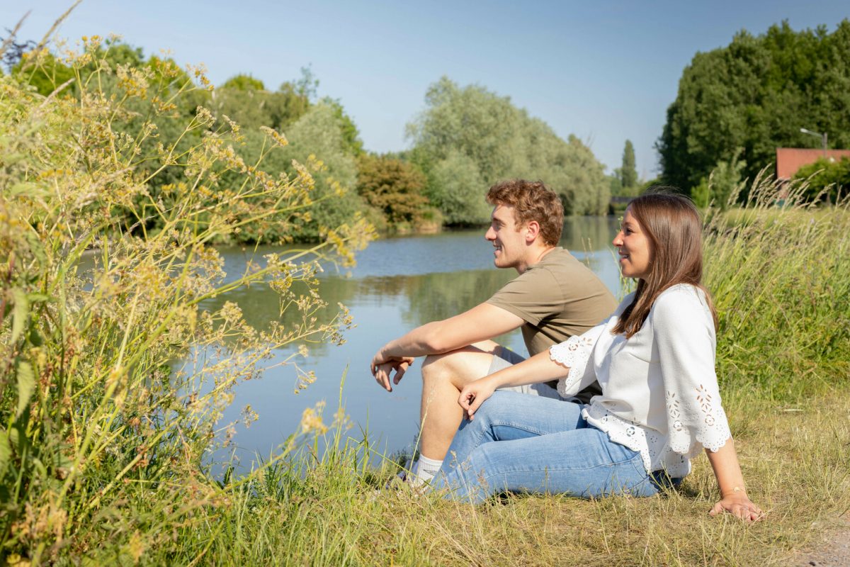 Jeune couple assis au bord de la Scarpe dans le Nord de la France